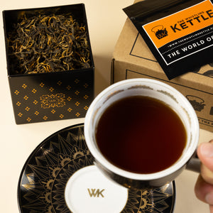 Cup & Saucer filled with brewed Ancient Forest held up next to Tea Tin filled with Ancient Forest loose leaf tea.