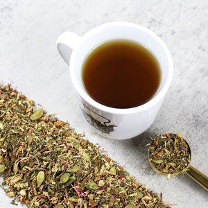 Cup of Belly Buddy tea next to mound of Belly Buddy tea leaves.