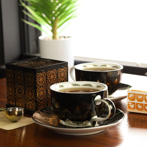 Cup & Saucers filled with brewed English Breakfast tea next to Tea Tin filled with English Breakfast loose leaf tea.