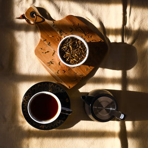 Golden Yunnan tea leaves, drink, and Nordic Tea Pot on table