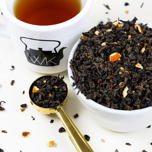 Cup of brewed Orange Ginger next to bowl of Orange Ginger loose leaf tea.