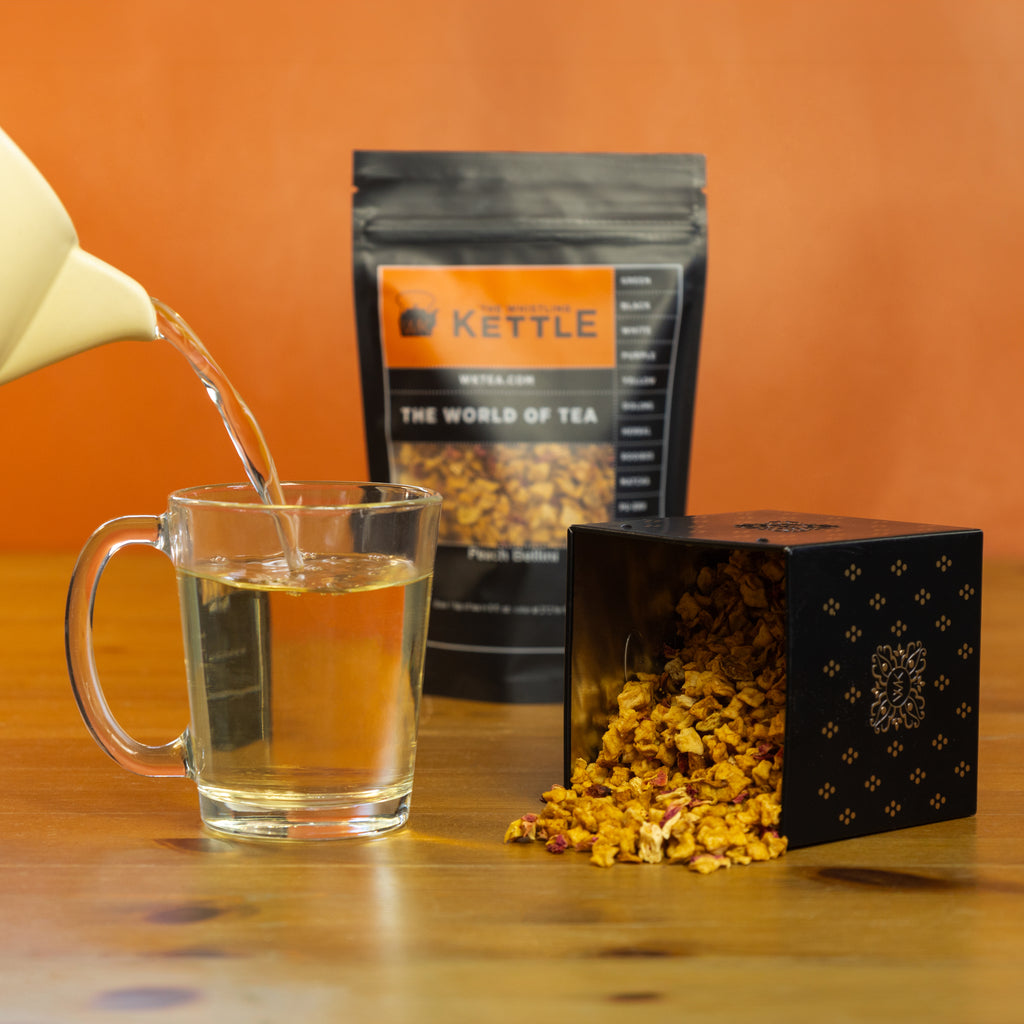 Peach Bellini being poured into glass next to tea tin with Peach Bellini loose leaf tea.