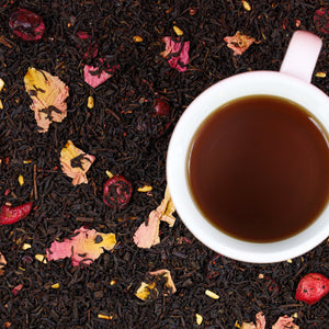 Cup of brewed Pomegranate Cranberry on top of Pomegranate Cranberry loose leaf tea.