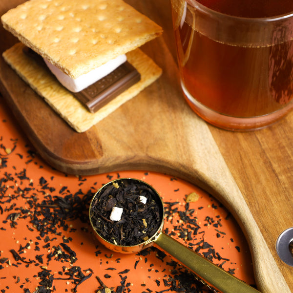 S'mores Toffee Crunch tea next to a s'mores and tea leaves.