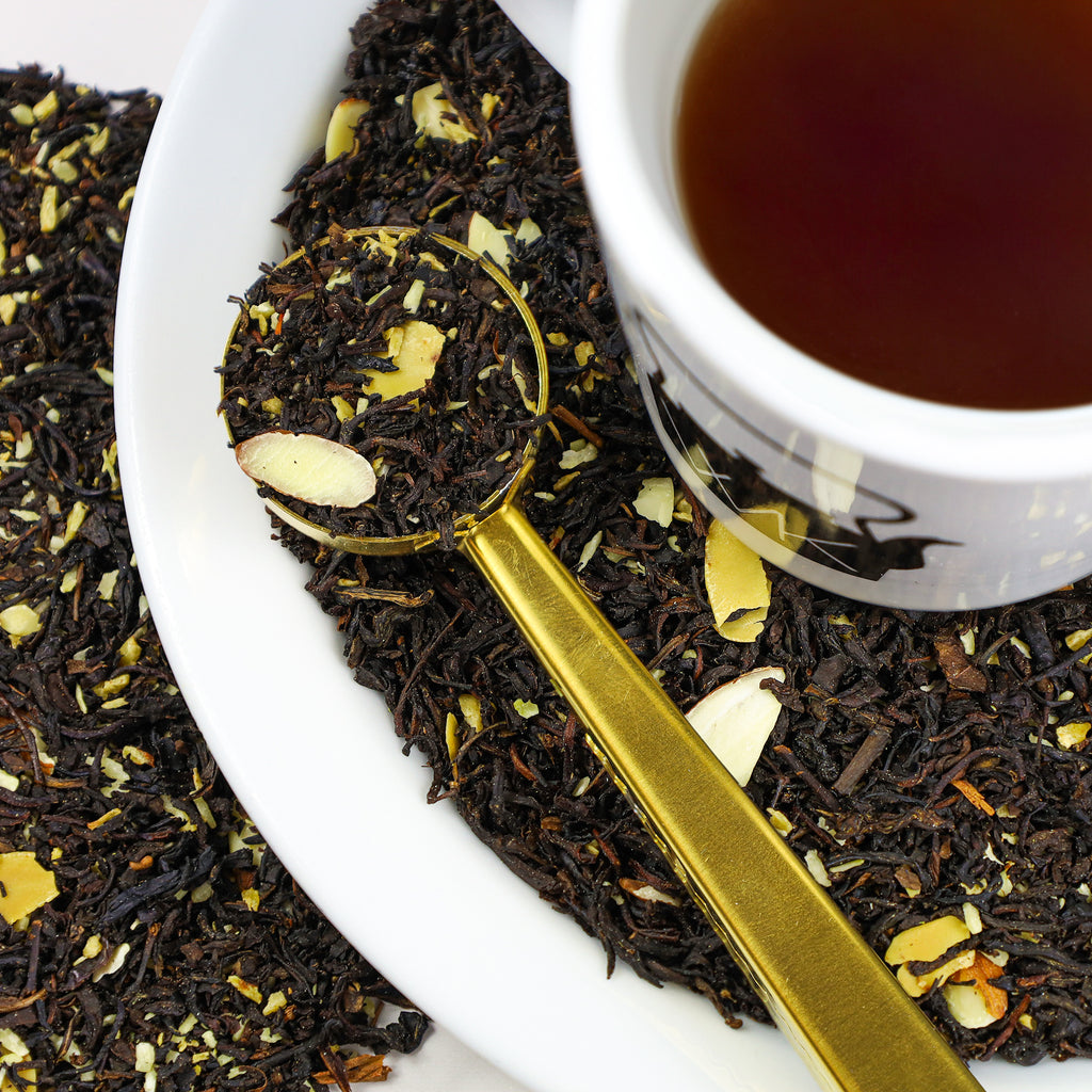 Cup of Snowflake on top of plate and next to Gold Tea Scoop, both filled with Snowflake loose leaf tea. 