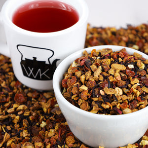 Cup of brewed Strawberry Kiwi next to bowl of Strawberry Kiwi loose leaf tea.