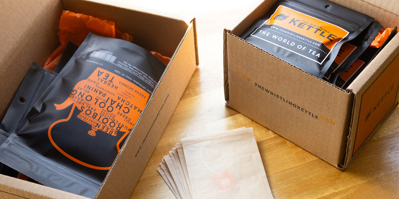 A Deluxe Tea of the Month box sits on a table next to a Sampler box